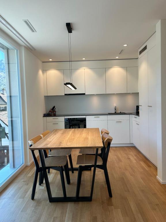 a kitchen with a wooden table and chairs at The R Apartment Passwang, KLIMA, NEU, Balkon, Parking in Balsthal