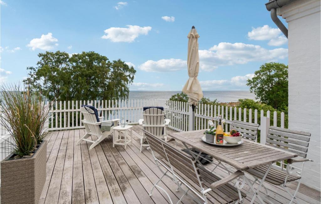 une terrasse en bois avec une table et des chaises et l'océan dans l'établissement Amazing Apartment In Svaneke With Wifi And 2 Bedrooms, à Svaneke