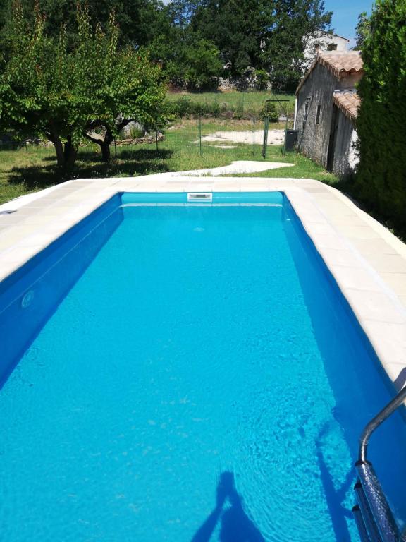 une piscine bleue dans une cour arborée dans l'établissement Villa de campagne avec piscine privé proximité Ardèche, à Saint-Paulet-de-Caisson