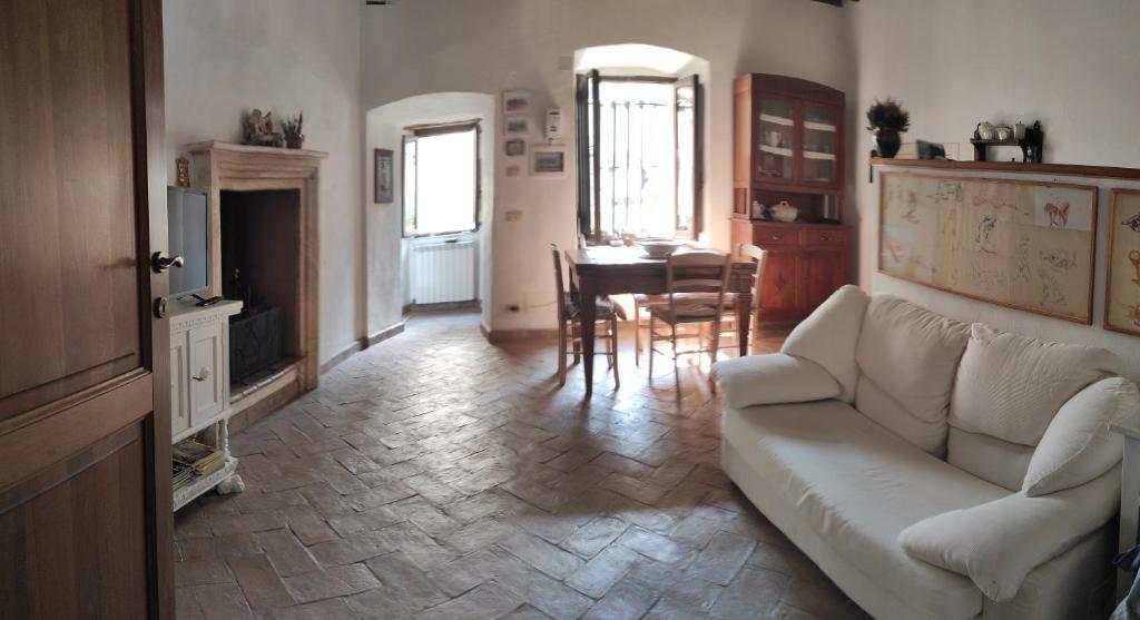 een woonkamer met een witte bank en een tafel bij Dormire nel Castello in Pitigliano