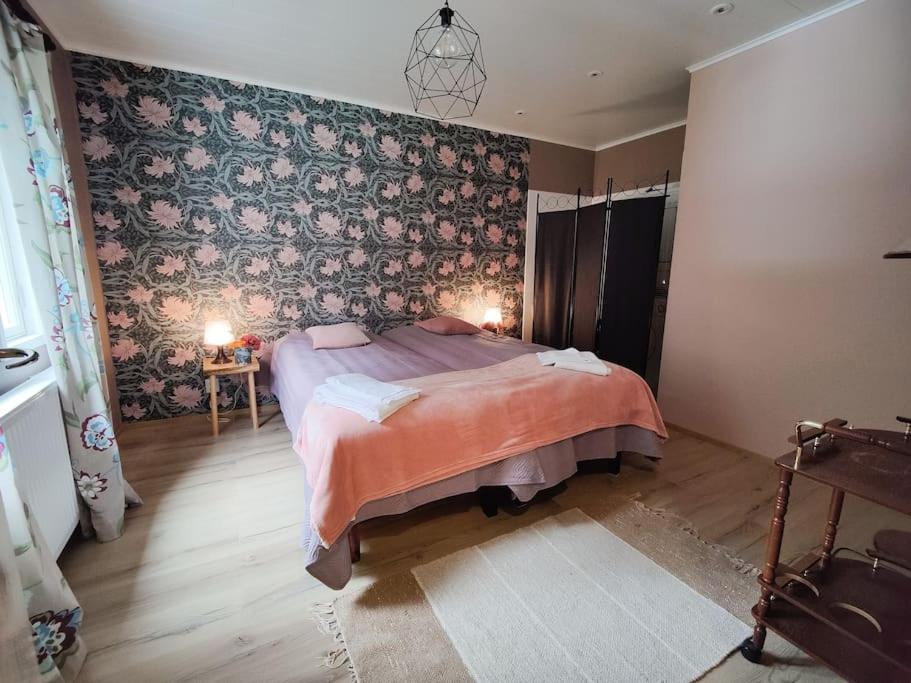 1 dormitorio con cama y pared con papel pintado con motivos florales en Ruma ankanpoikanen, en Pori