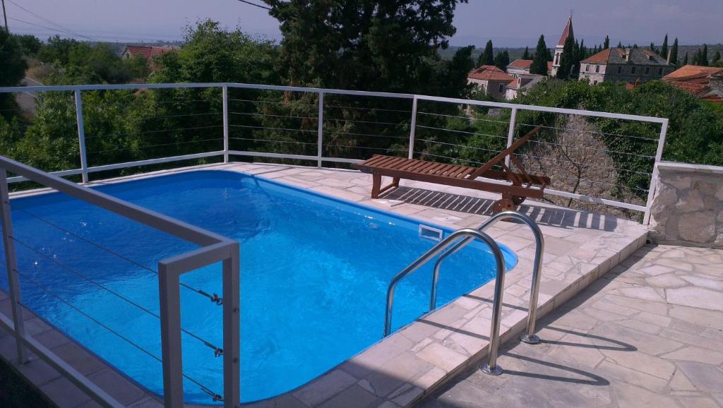 a swimming pool with a bench next to a fence at Holiday Home Bobovisca in Ložišće