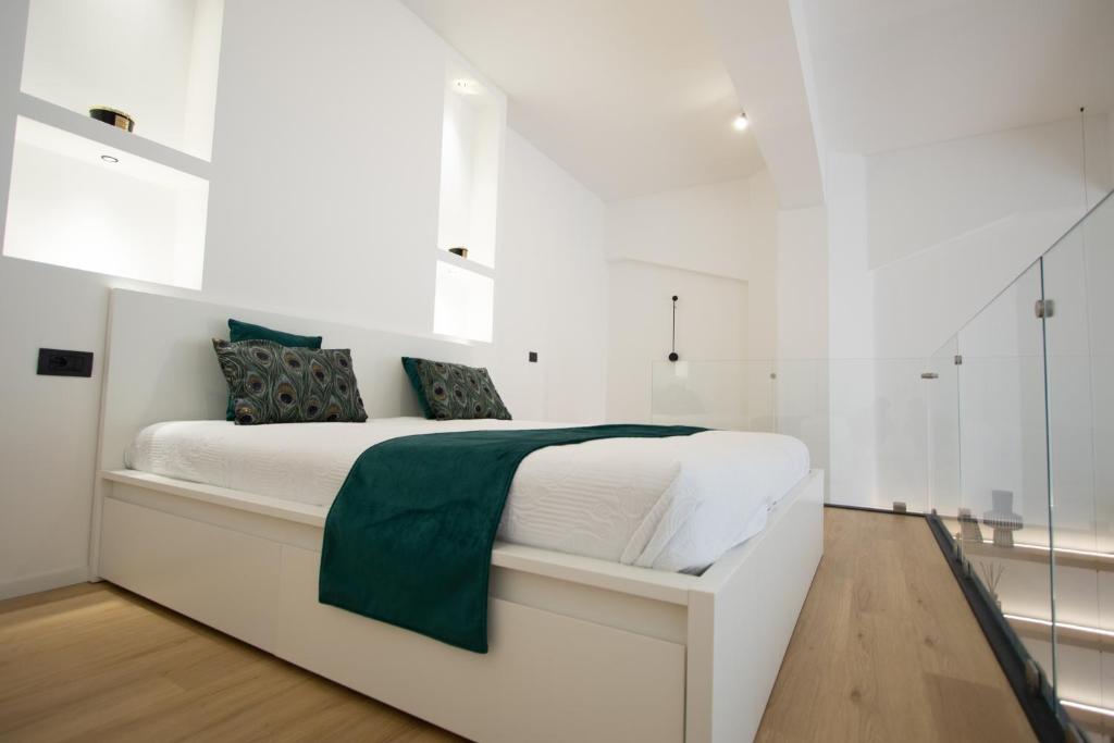 Dormitorio blanco con cama blanca y manta verde en Loft Milano Manifatture2, en Milán