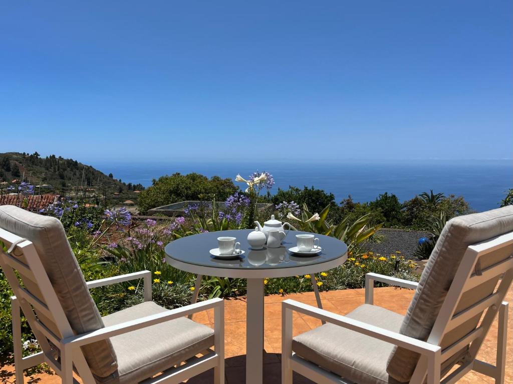 una mesa y sillas en un patio con el océano en el fondo en Casa Lucia, en Puntagorda
