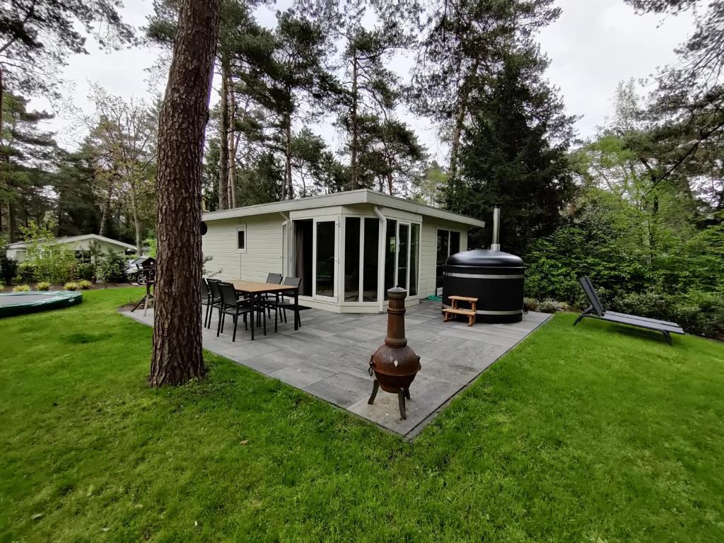 een achtertuin met een grill en een huis bij Huisje Weltevree met hottub in Beekbergen