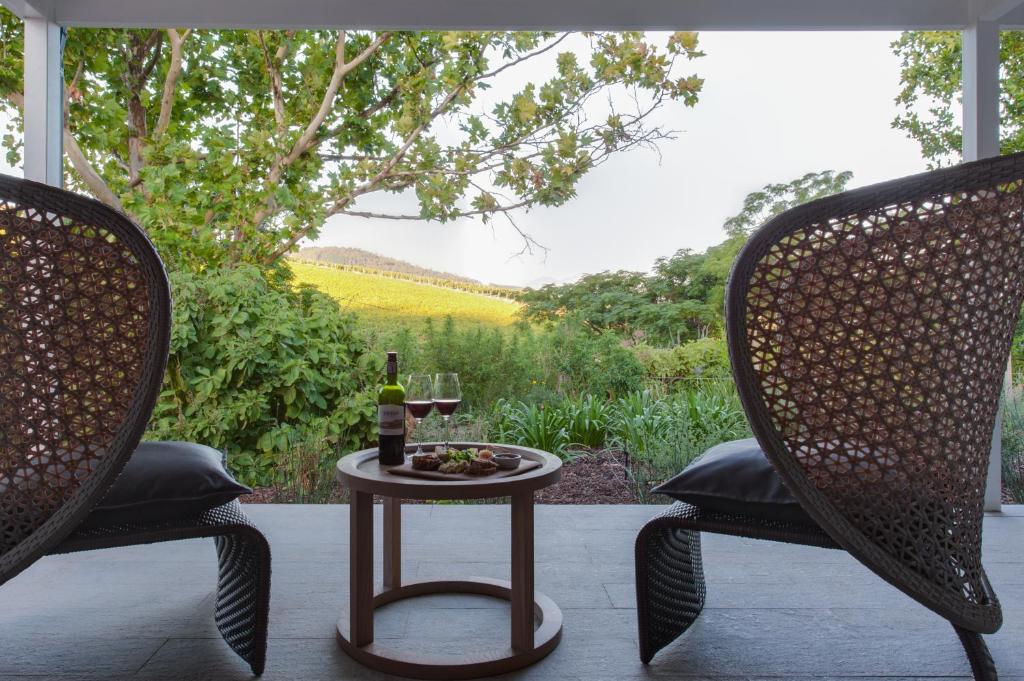 twee stoelen en een tafel met een glas wijn op een patio bij The Jordan Suites in Stellenbosch