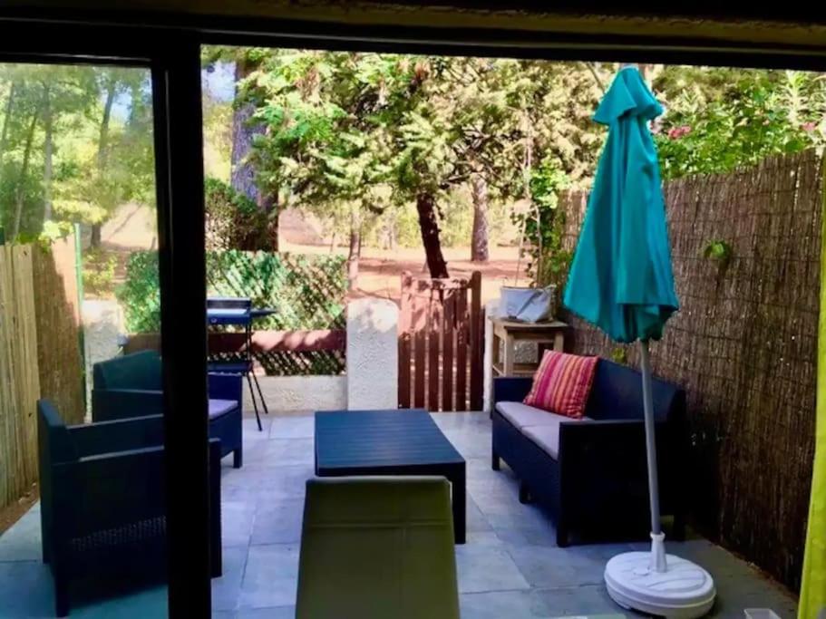 une terrasse avec des chaises, un parasol et une table dans l'établissement Plage & Soleil, Charmant Studio 5 minutes à pied du port et de la plage, à Saint-Cyr-sur-Mer