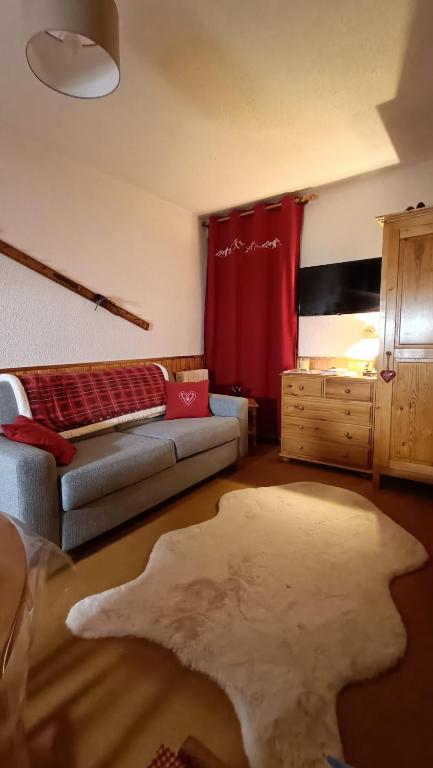 - un salon avec un canapé et un rideau rouge dans l'établissement Appartement pied des pistes - Samoëns 1600, à Samoëns