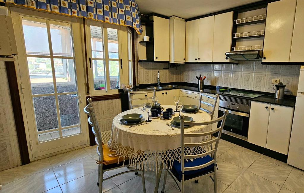 uma cozinha com uma mesa e cadeiras numa cozinha em A pie de playa em Vilariño