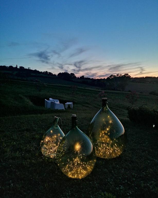 trzy szklane butelki z oświetleniem w polu w obiekcie Il Giardino nella Valle w mieście Belvedere Ostrense