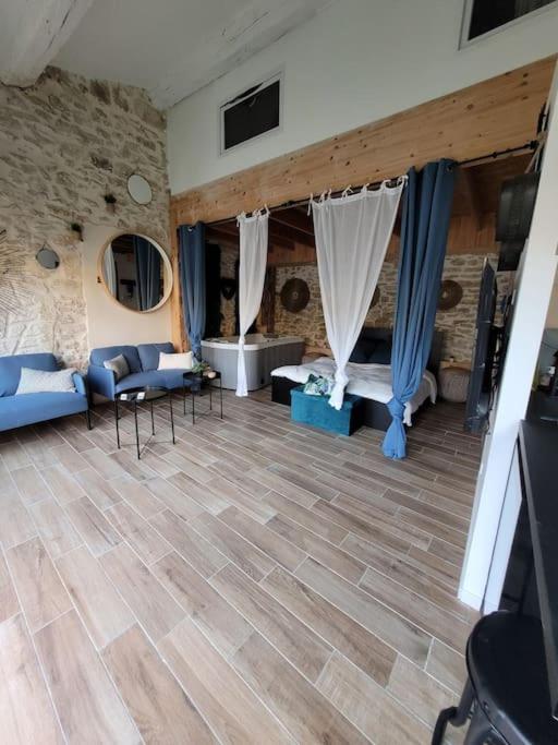 una sala de estar con suelo de madera y una habitación con sofá en Studio de charme - Le Céleste, en Vergèze