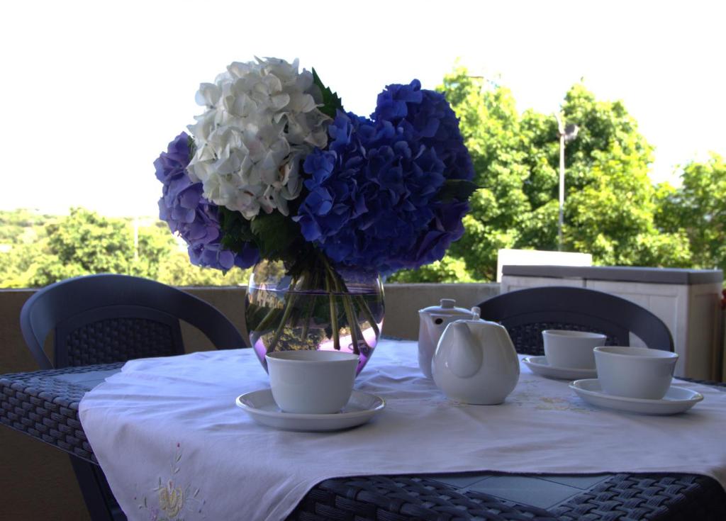 uma mesa com um vaso de flores azuis e brancas em La casa di Noemi em Tempio Pausania