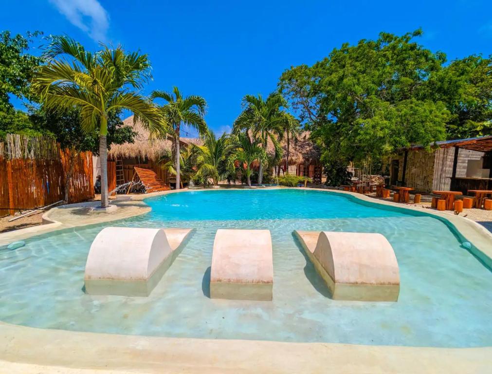 a large swimming pool with palm trees and blue skies at Xhule Hotel Boutique in Tulum