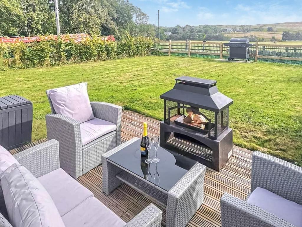 a grill on a patio with chairs and a table at Acre Hill Cottage in Harrop Fold