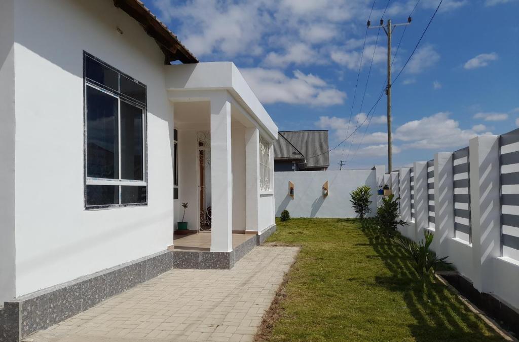 ein weißes Haus mit einem Zaun davor in der Unterkunft La-Domek Traveller's home in Mbeya