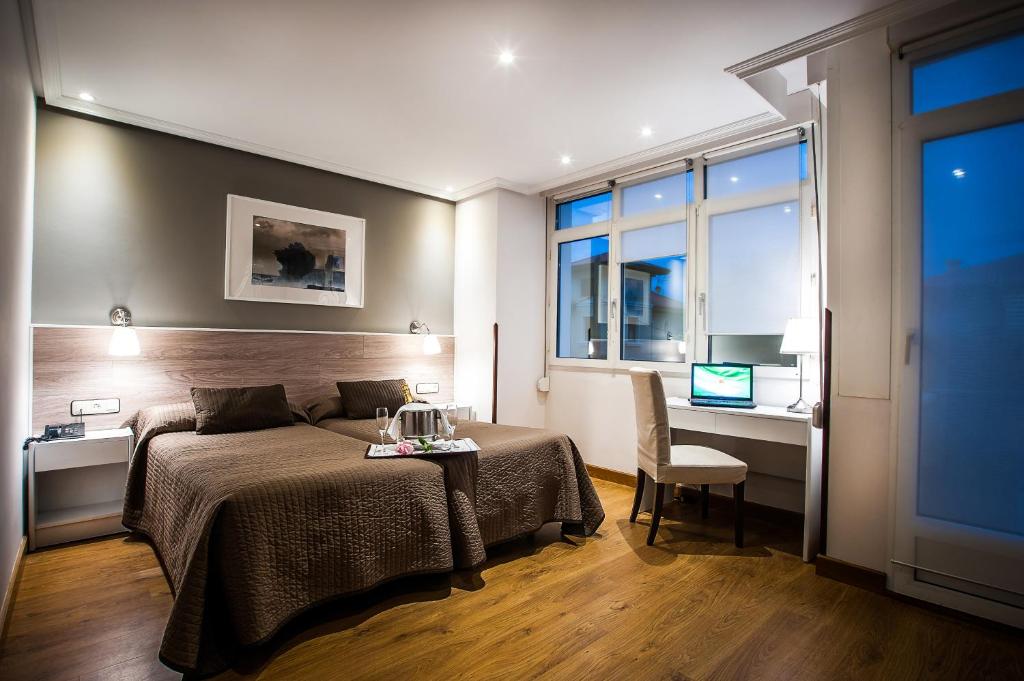 a bedroom with a bed and a desk and a computer at Hotel Don Pepe Ria in Ribadesella