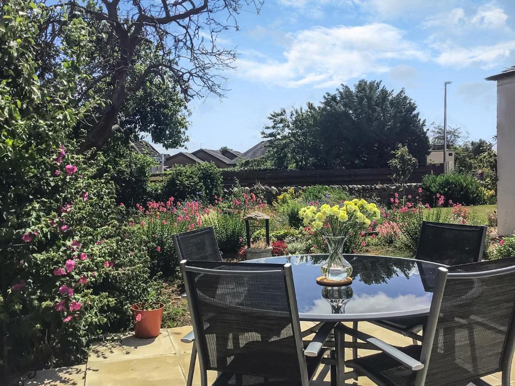 un tavolo e sedie in un giardino fiorito di The Bungalow a Carnoustie
