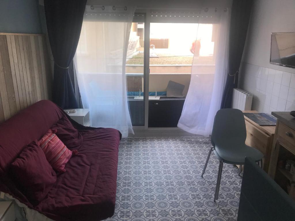 a living room with a couch and a desk and a window at Location Sète les pieds dans l&#39;eau in Sète