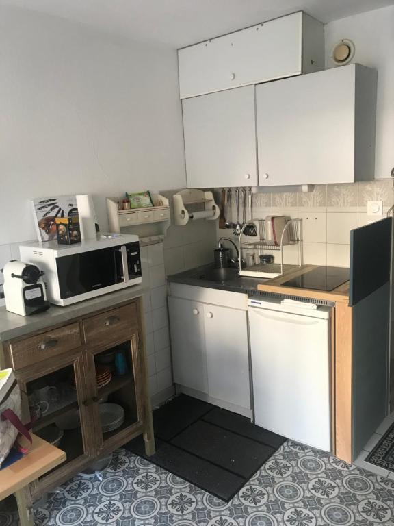 a small kitchen with white cabinets and a microwave at Location Sète les pieds dans l&#39;eau in Sète