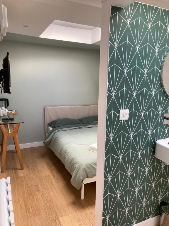ein Schlafzimmer mit einem Bett mit einer grünen Wand in der Unterkunft Central ensuite guest unit with free on-street parking in Brighton & Hove