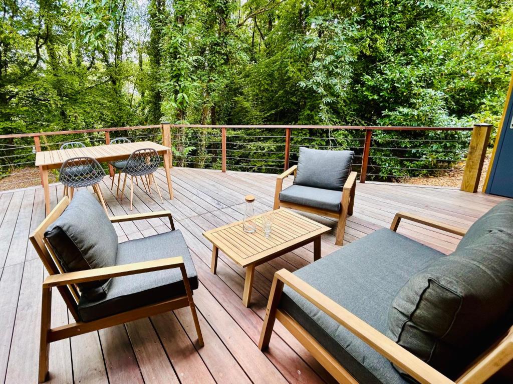 een terras met een bank, stoelen en een tafel bij Lodge avec spa au coeur de Brocéliande in Beignon