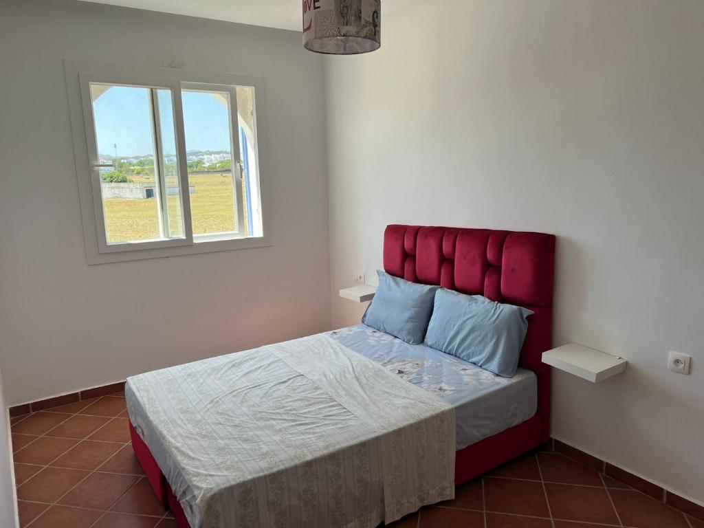 a bedroom with a bed with a red headboard and a window at Un bel appartement à Mirador Golf 2 in Cabo Negro