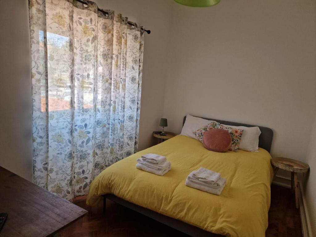 a bedroom with a yellow bed with towels on it at Alojamento Mercado Norte in Lisbon