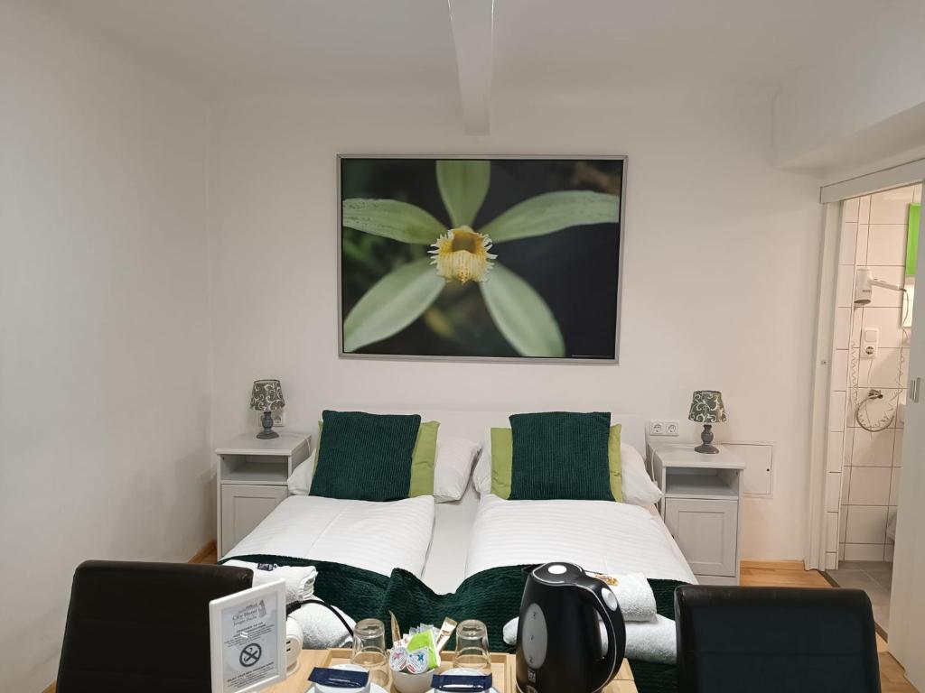ein Schlafzimmer mit einem Bett mit grünen Kissen und einem Tisch in der Unterkunft Cityhotel Junger Fuchs in Salzburg