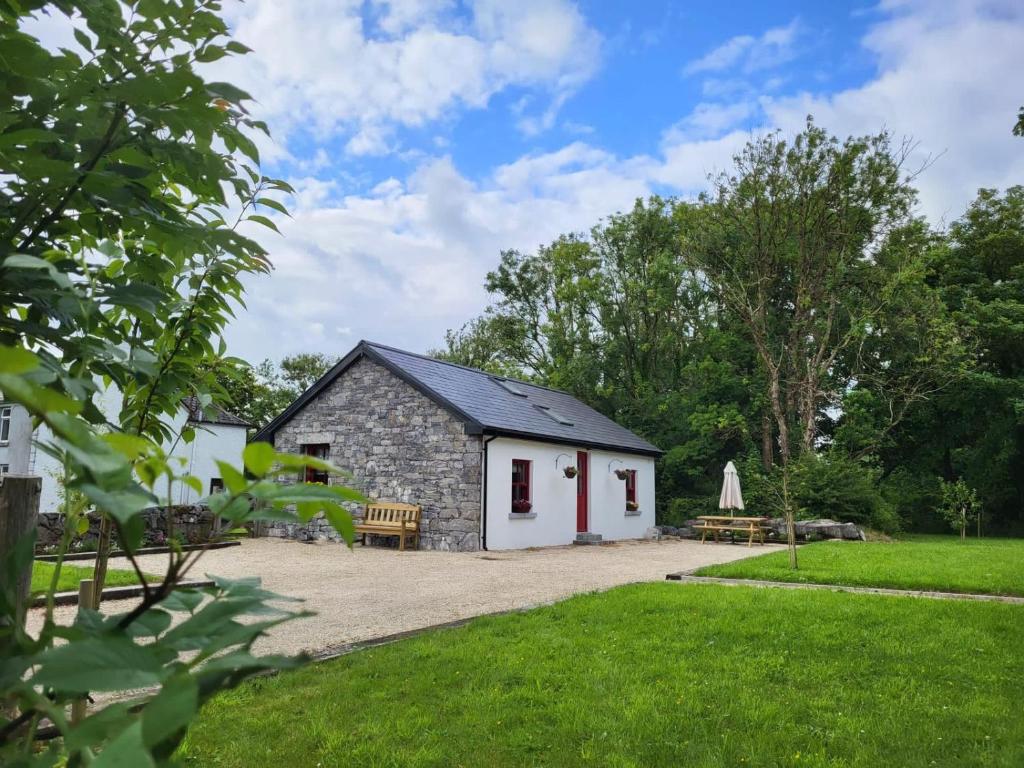 a stone cottage with a bench and a picnic table at Teresa's Cottage in Kilcolgan