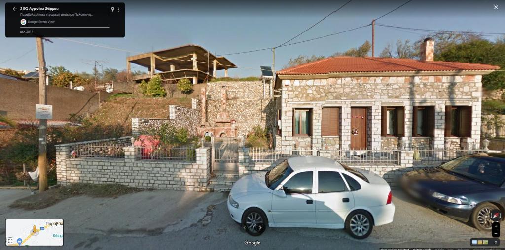biały samochód zaparkowany przed domem w obiekcie Αρχωντικα στην Τρiχονιδα w mieście Agrinio