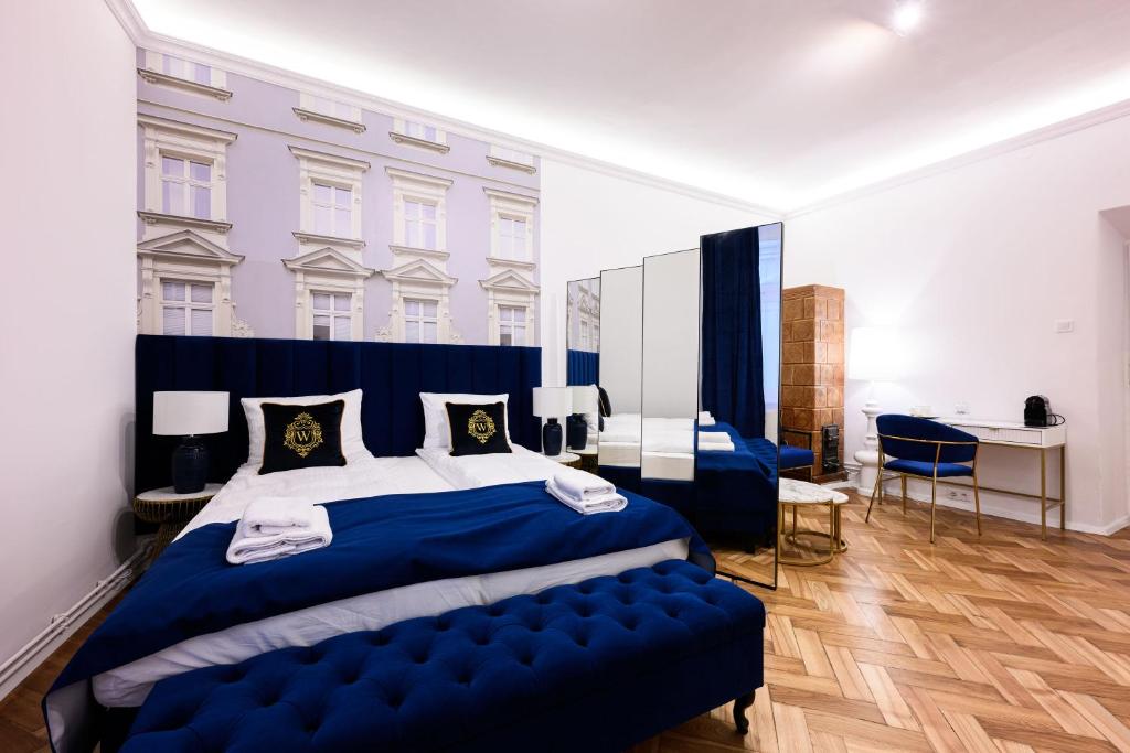 a bedroom with a large blue bed with a blue bench at Wiślna Main Square Apartments in Krakow