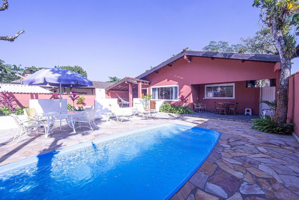 a swimming pool with chairs and an umbrella and a house at Nova, piscina exclusiva, 350 m. de Camburizinho in Camburi