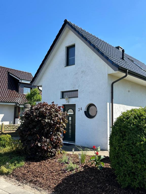 a white house with a black door and bushes at Ferienhaus Kottmann in Bremerhaven