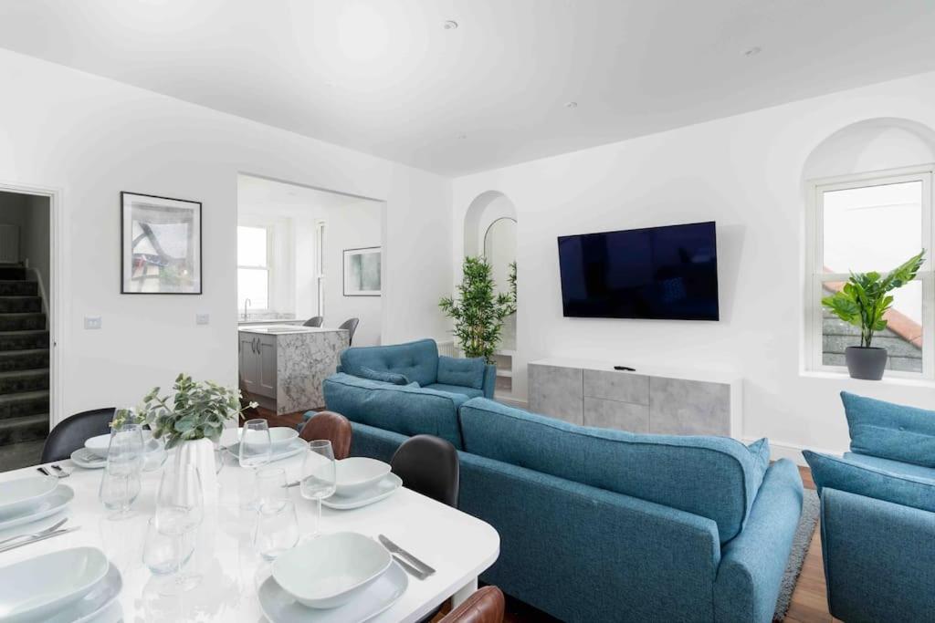 een woonkamer met een tafel en blauwe banken bij 3 Bed, sea views, central Penzance,newly renovated in Penzance