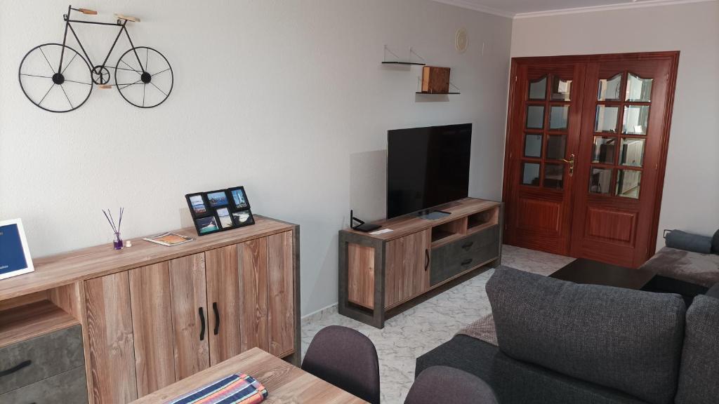 a living room with a tv and a bike on the wall at Apartamento A Atalaia in Laxe