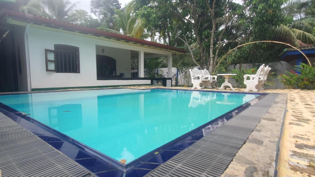 a swimming pool in front of a house at The river lake villa in Unawatuna