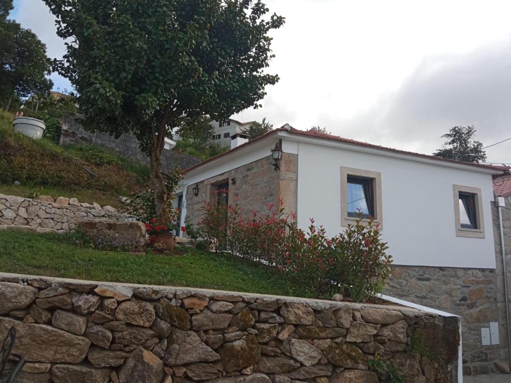 uma casa branca com uma parede de pedra em frente em Casa Tia Vina - Serra em Arouca