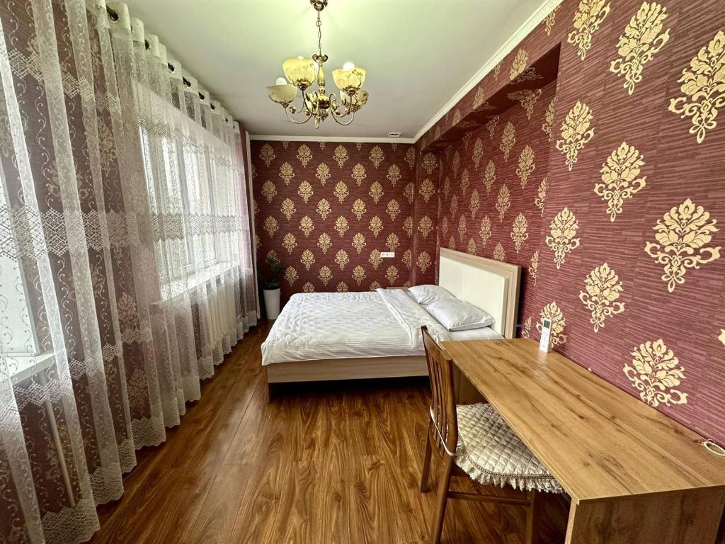 a bedroom with a bed and a table and curtains at Hostel 4U in Bishkek