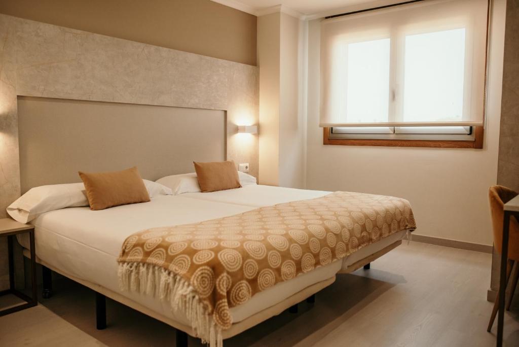 1 dormitorio con 1 cama blanca grande y ventana en PENSIÓN BERENGUELA, en Melide