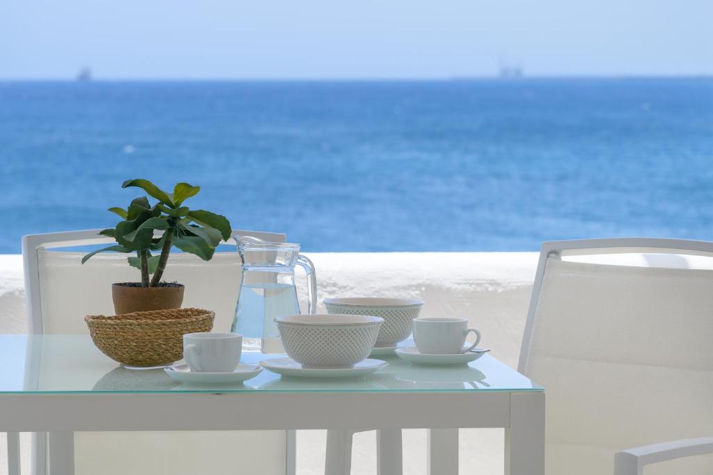 una mesa blanca con tazas y una maceta en ella en La Vida Oceana, en Costa Teguise
