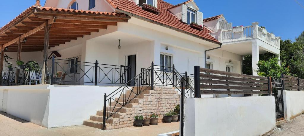 a white house with stairs in front of it at Grand Chalet Cottage House in Porto Rafti