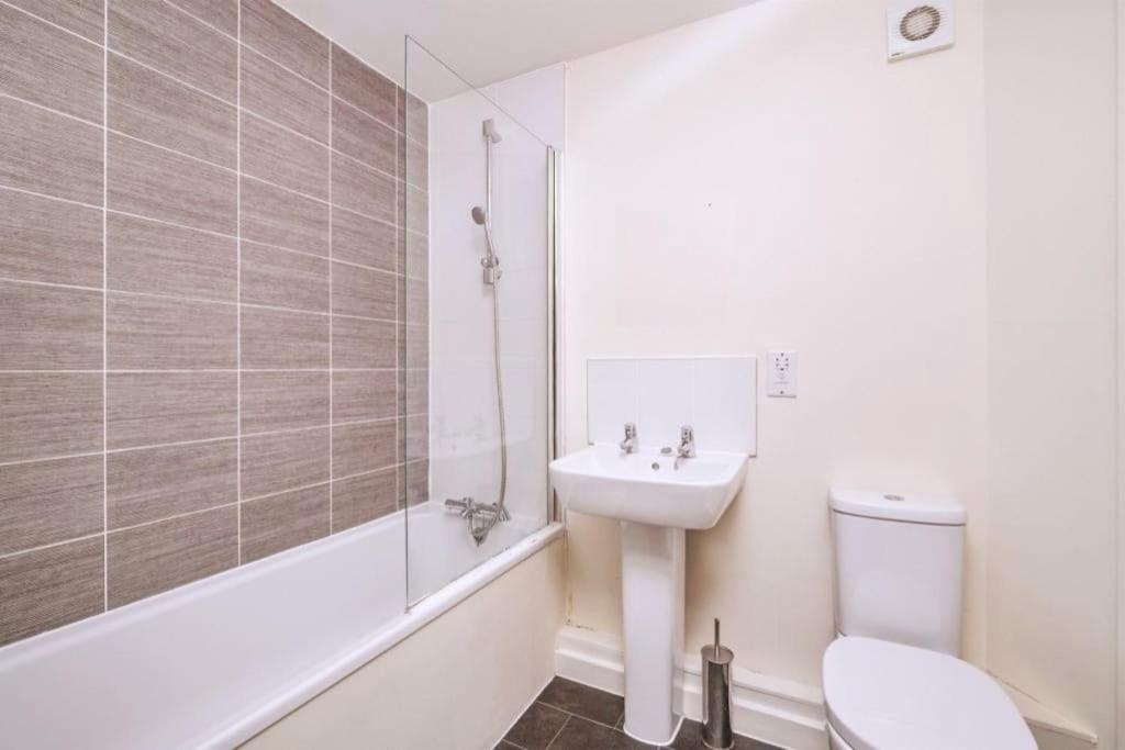 a bathroom with a sink and a toilet and a tub at Sianavi Apartments in Kettering