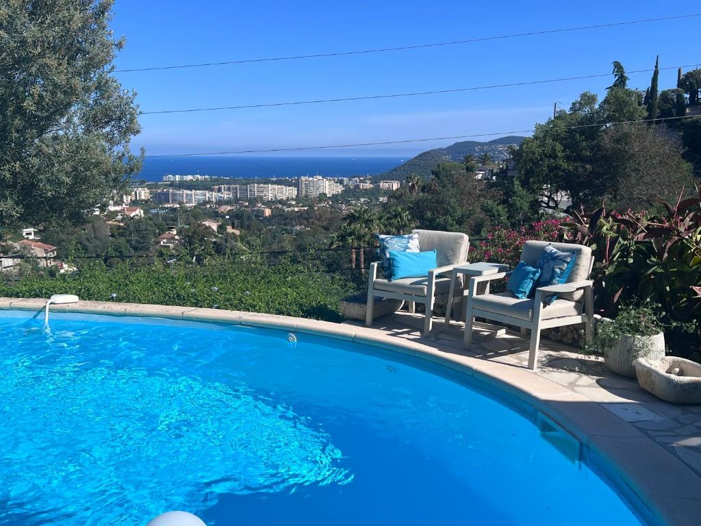 einen Pool mit Stühlen und Meerblick in der Unterkunft Fantastic villa in the bay of Cannes, 5 minutes from the beach - with heated private pool in Mandelieu-la-Napoule