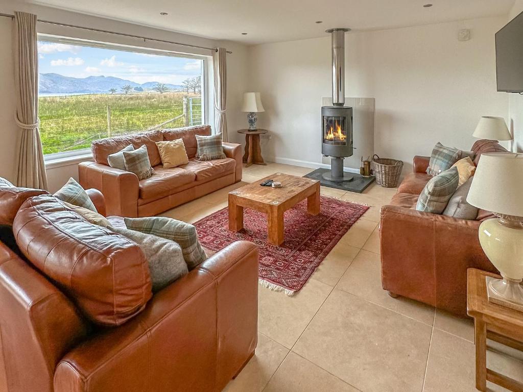 a living room with leather furniture and a fireplace at Lurach House - Ukc6791 in Port Appin