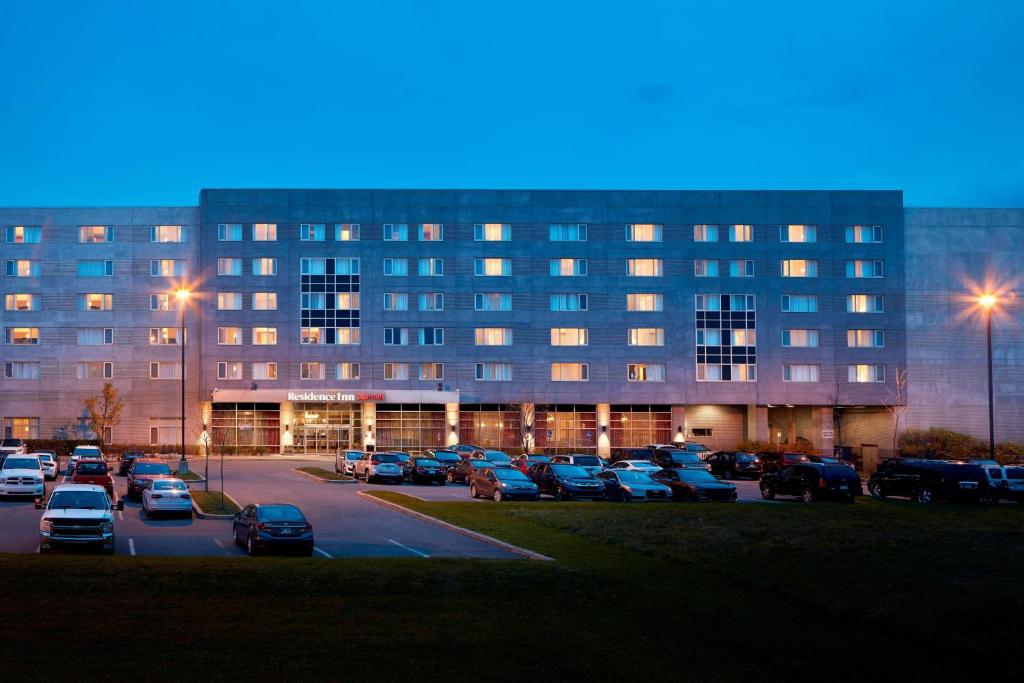 a large building with cars parked in a parking lot at Residence Inn by Marriott Montreal Airport in Dorval