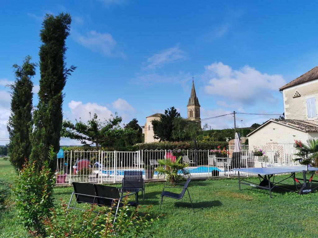 un cortile con tavolo, sedie e recinzione di Les volets bleus a Doudrac