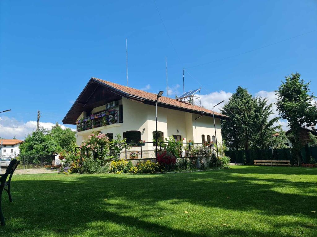 uma casa com um relvado verde em frente em Villa Janet em Dolna Banya