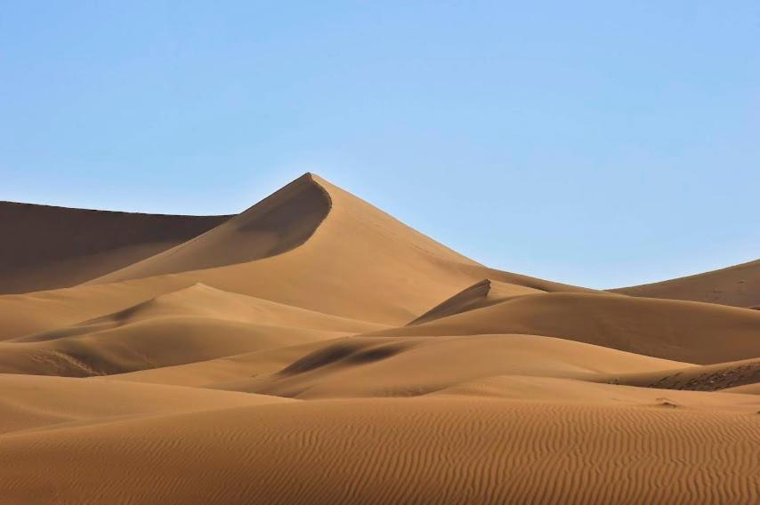un grupo de dunas de arena en el desierto en Zaila Erg Chigaga Luxury Camp, en Mhamid