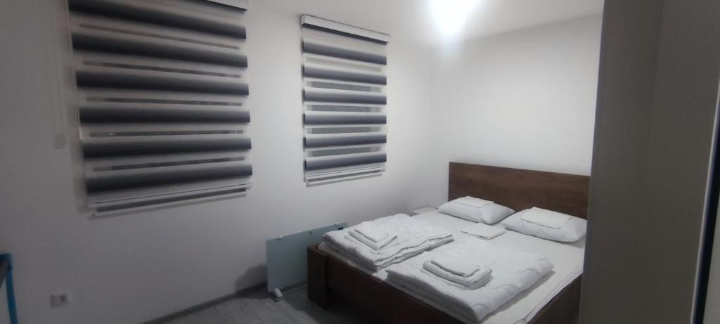 um pequeno quarto com uma cama com lençóis brancos e almofadas em Perfect Holidays em Vlasic