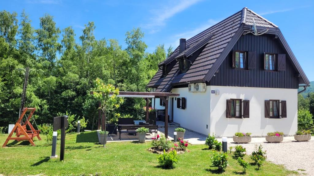 ein kleines Haus mit schwarzem Dach in der Unterkunft B&B Plitvice Lakes Villa Mija in Plitvica Selo